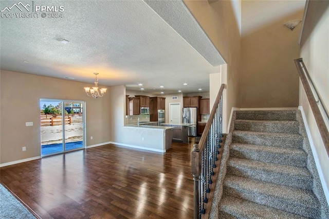 stairs featuring wood-type flooring, a textured ceiling, and a notable chandelier