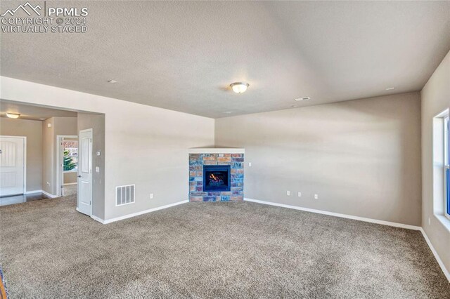 10978 Middlegate Ct, Peyton, CO 80831 - unfurnished living room with carpet floors, baseboards, a textured ceiling, and a lit fireplace