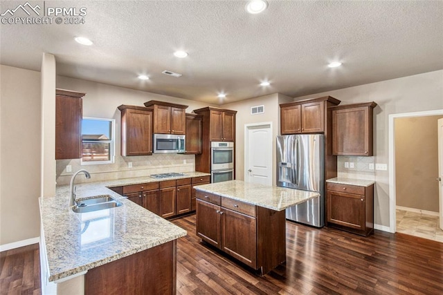 10978 Middlegate Ct, Peyton, CO 80831 - kitchen featuring appliances with stainless steel finishes, a sink, tasteful backsplash, light stone counters, and a textured ceiling