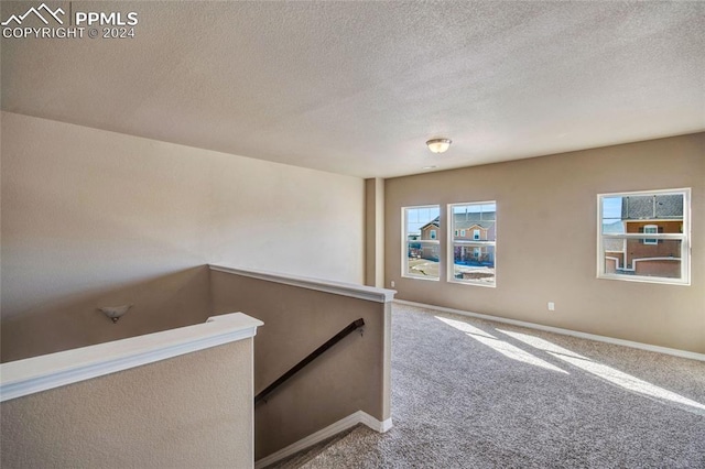 hallway with carpet and a textured ceiling