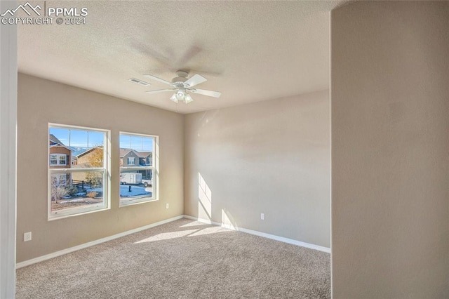 carpeted empty room with ceiling fan and a textured ceiling