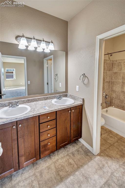 10978 Middlegate Ct, Peyton, CO 80831 - bathroom with double vanity, bathtub / shower combination, toilet, a textured wall, and baseboards
