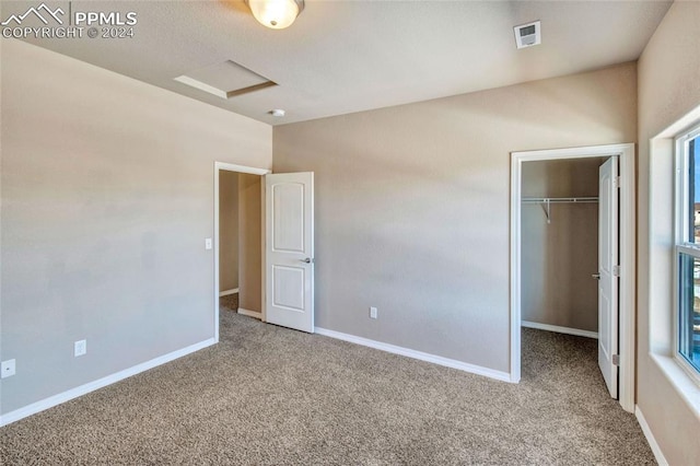 unfurnished bedroom with carpet flooring, a spacious closet, and a closet