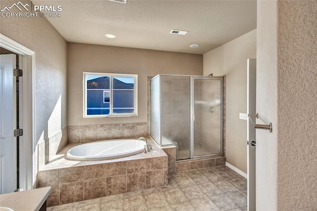 bathroom featuring vanity, independent shower and bath, and a textured ceiling