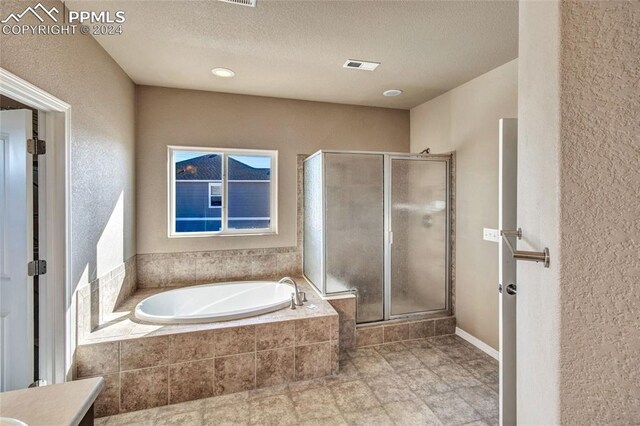 10978 Middlegate Ct, Peyton, CO 80831 - full bath with a garden tub, a shower stall, a textured ceiling, vanity, and a textured wall