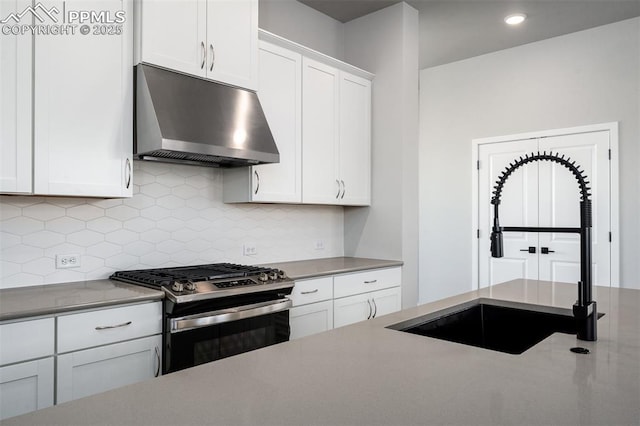 kitchen featuring white cabinetry, sink, stainless steel gas range, range hood, and backsplash