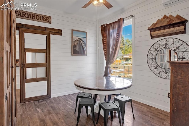 dining area with dark wood-type flooring, wood walls, and a wall mounted AC