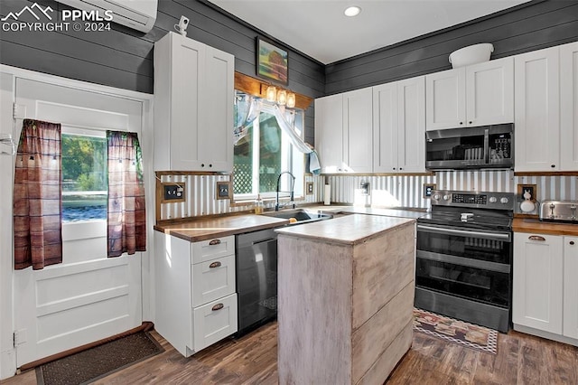 kitchen featuring wood walls, white cabinetry, sink, black appliances, and dark hardwood / wood-style floors