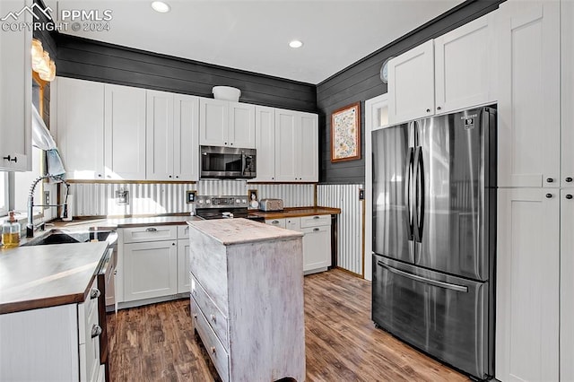 kitchen with stainless steel appliances, dark hardwood / wood-style flooring, white cabinets, and a kitchen island