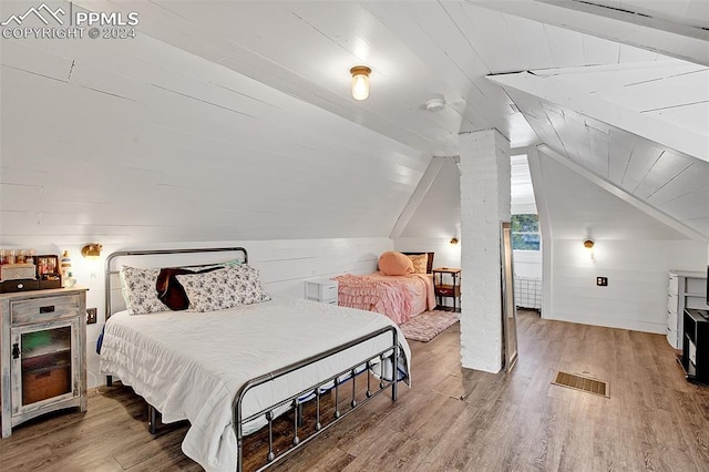 bedroom featuring hardwood / wood-style floors, wooden walls, and vaulted ceiling