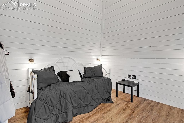 bedroom featuring wood walls and hardwood / wood-style flooring