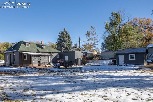 snow covered house featuring an outbuilding