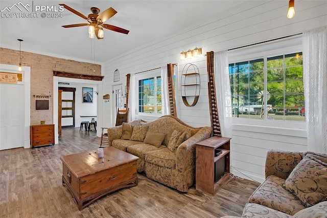 living room featuring ceiling fan, wood-type flooring, and wooden walls