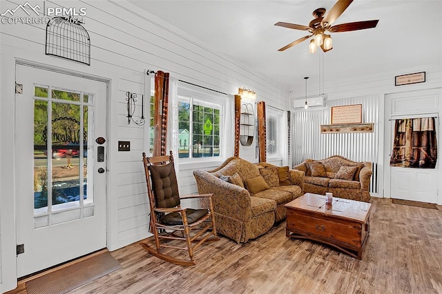 living room with wood walls, a wealth of natural light, hardwood / wood-style floors, and ceiling fan