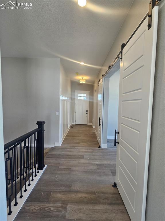 hallway featuring a barn door and dark wood-type flooring