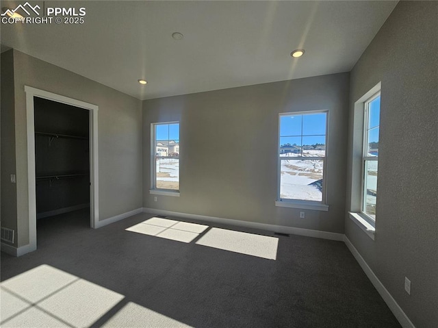 unfurnished bedroom featuring dark colored carpet, a spacious closet, and a closet