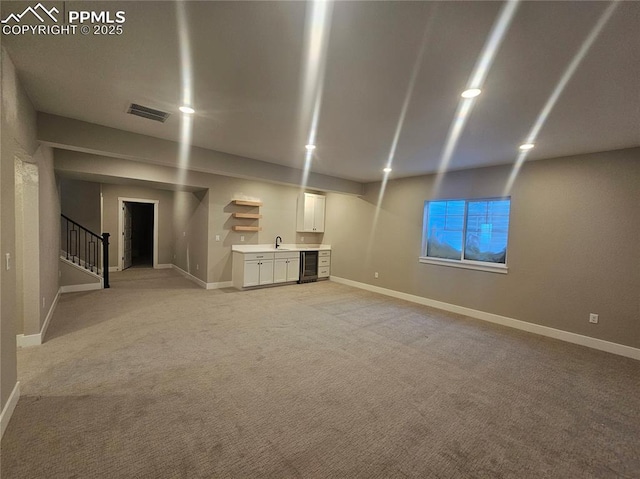 basement featuring sink, light colored carpet, and beverage cooler