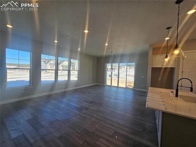 unfurnished living room with a textured ceiling, sink, and dark wood-type flooring