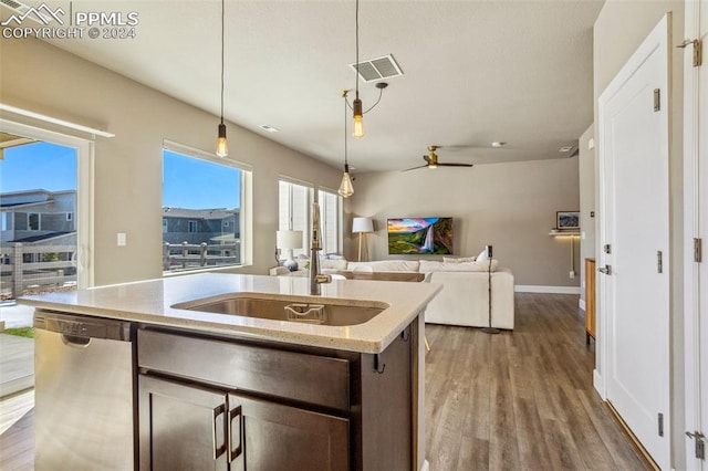 kitchen with a center island with sink, stainless steel dishwasher, dark brown cabinetry, decorative light fixtures, and wood-type flooring