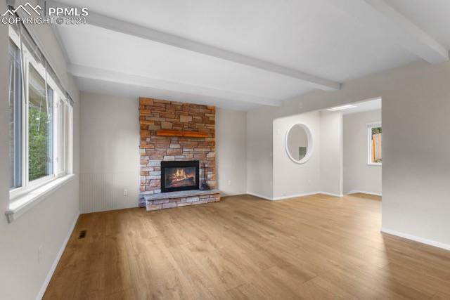 unfurnished living room featuring a fireplace, hardwood / wood-style floors, and beam ceiling