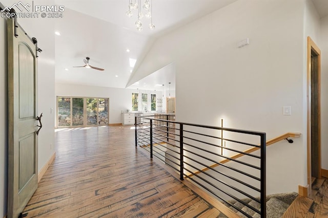 hall with hardwood / wood-style floors, a barn door, vaulted ceiling, and a notable chandelier