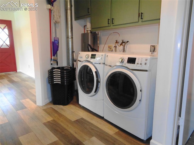 laundry area with water heater, light hardwood / wood-style flooring, cabinets, and independent washer and dryer