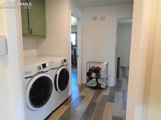 laundry area featuring dark wood-type flooring, cabinets, and washer and clothes dryer