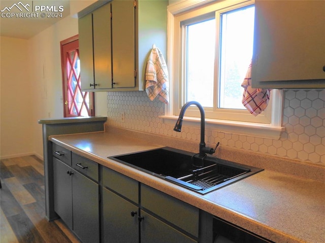 kitchen with dark wood-type flooring, green cabinets, sink, and backsplash