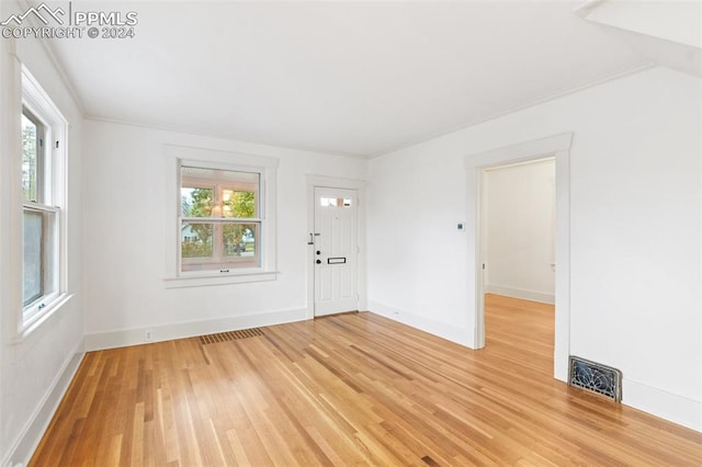 spare room featuring ornamental molding and light wood-type flooring