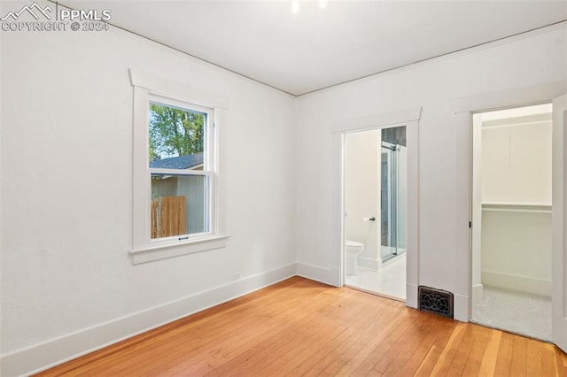 unfurnished bedroom featuring hardwood / wood-style flooring and connected bathroom