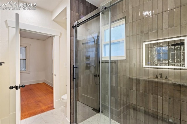 bathroom with hardwood / wood-style flooring, toilet, and an enclosed shower