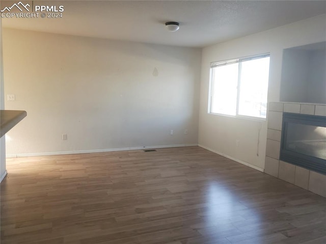 unfurnished living room with dark hardwood / wood-style flooring and a tile fireplace