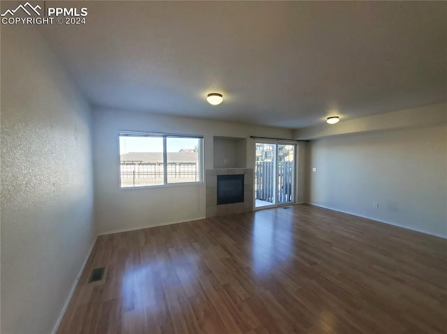 unfurnished living room featuring dark wood-type flooring and a tile fireplace