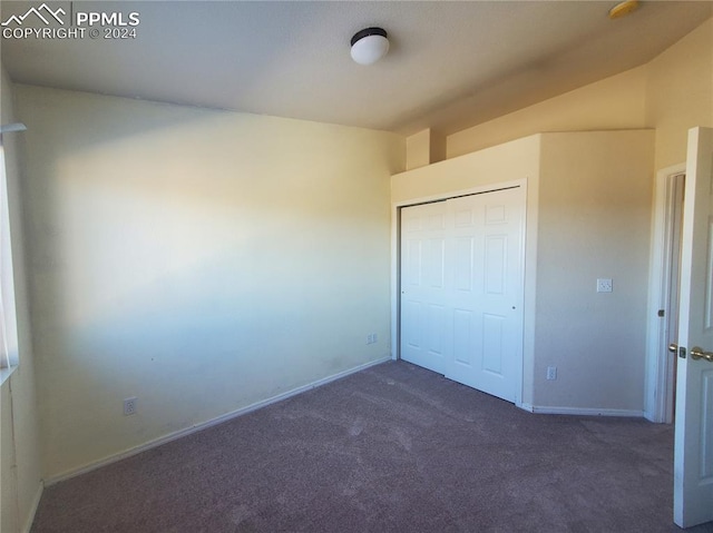 unfurnished bedroom with dark colored carpet and a closet