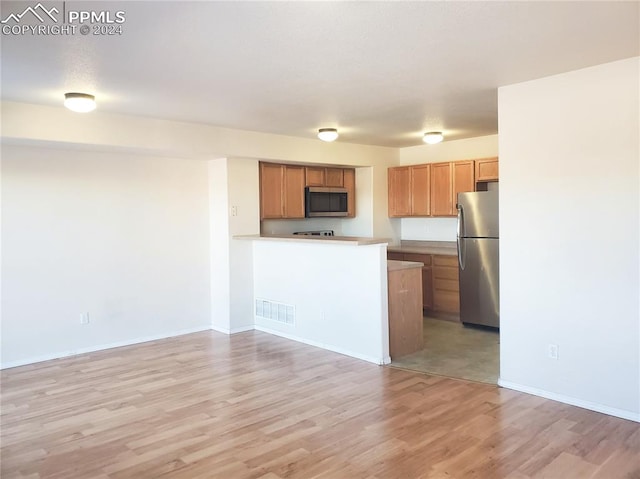 kitchen with kitchen peninsula, stainless steel appliances, and light hardwood / wood-style flooring