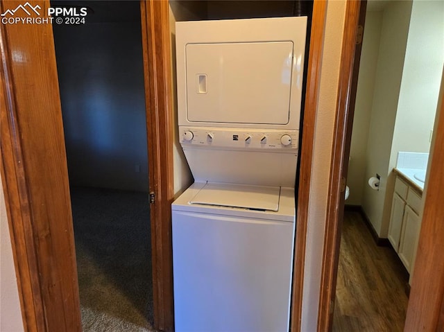 washroom with dark hardwood / wood-style floors and stacked washer / drying machine