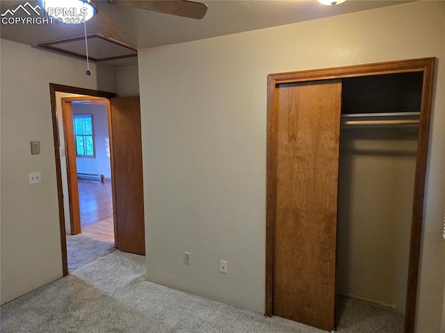 unfurnished bedroom with light carpet, baseboard heating, a closet, and ceiling fan