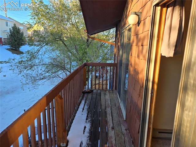 snow covered back of property featuring a baseboard heating unit