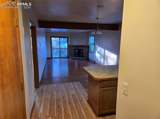 interior space with a fireplace, beamed ceiling, and wood-type flooring