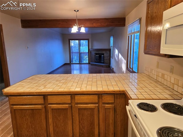 kitchen with tile counters, beamed ceiling, pendant lighting, and dark hardwood / wood-style floors