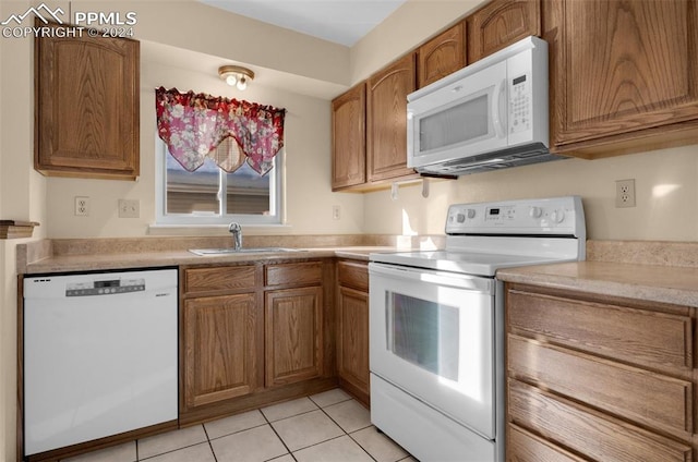 kitchen with light tile patterned floors, white appliances, and sink