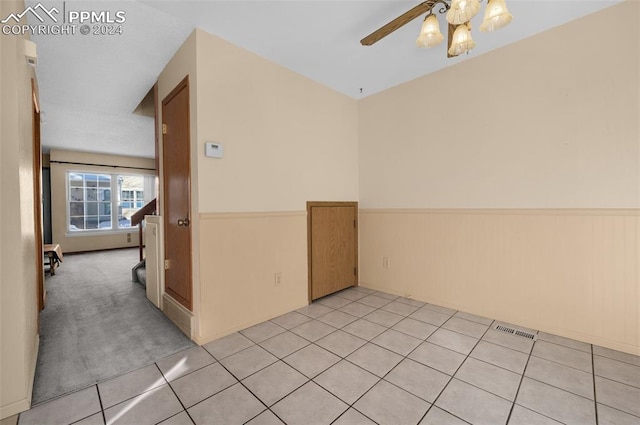 spare room with wood walls, light tile patterned floors, and ceiling fan