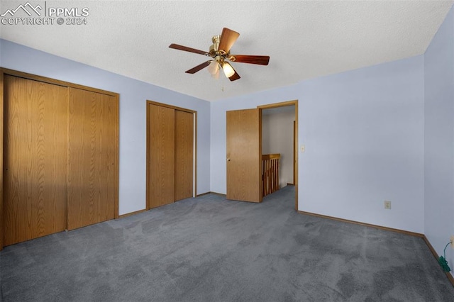 unfurnished bedroom featuring a textured ceiling, two closets, and ceiling fan