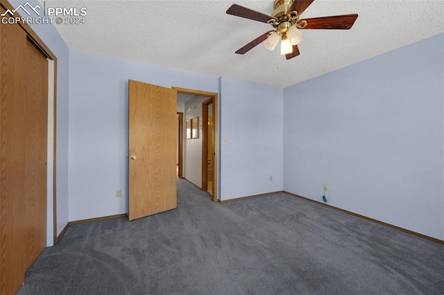 unfurnished bedroom featuring a closet, a textured ceiling, dark colored carpet, and ceiling fan