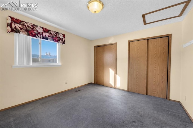 unfurnished bedroom with a textured ceiling, multiple closets, and carpet floors