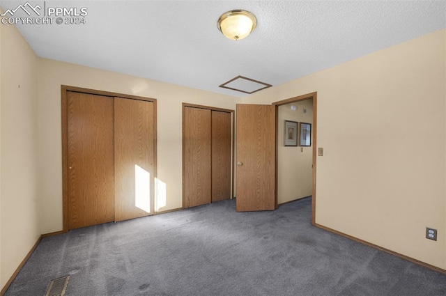 unfurnished bedroom featuring dark colored carpet and two closets