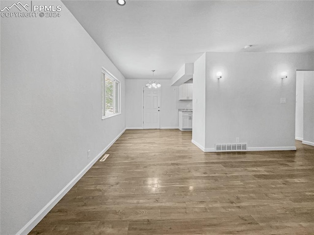 unfurnished living room featuring hardwood / wood-style floors and an inviting chandelier