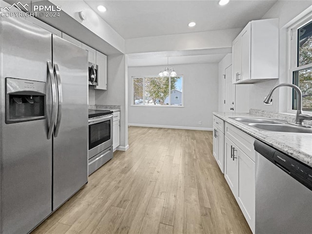 kitchen with plenty of natural light, appliances with stainless steel finishes, sink, and white cabinets