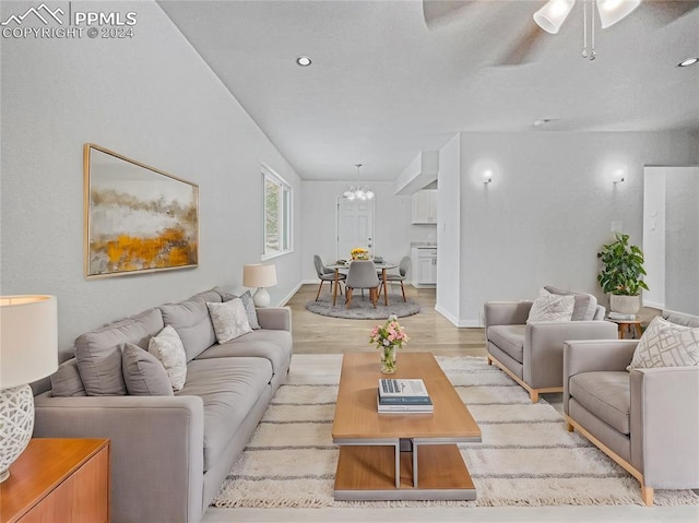 living room with ceiling fan with notable chandelier and light hardwood / wood-style floors