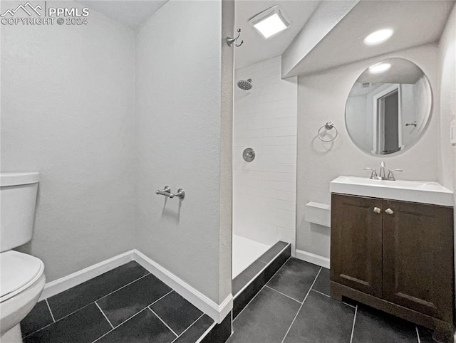 bathroom with toilet, vanity, tile patterned flooring, and tiled shower